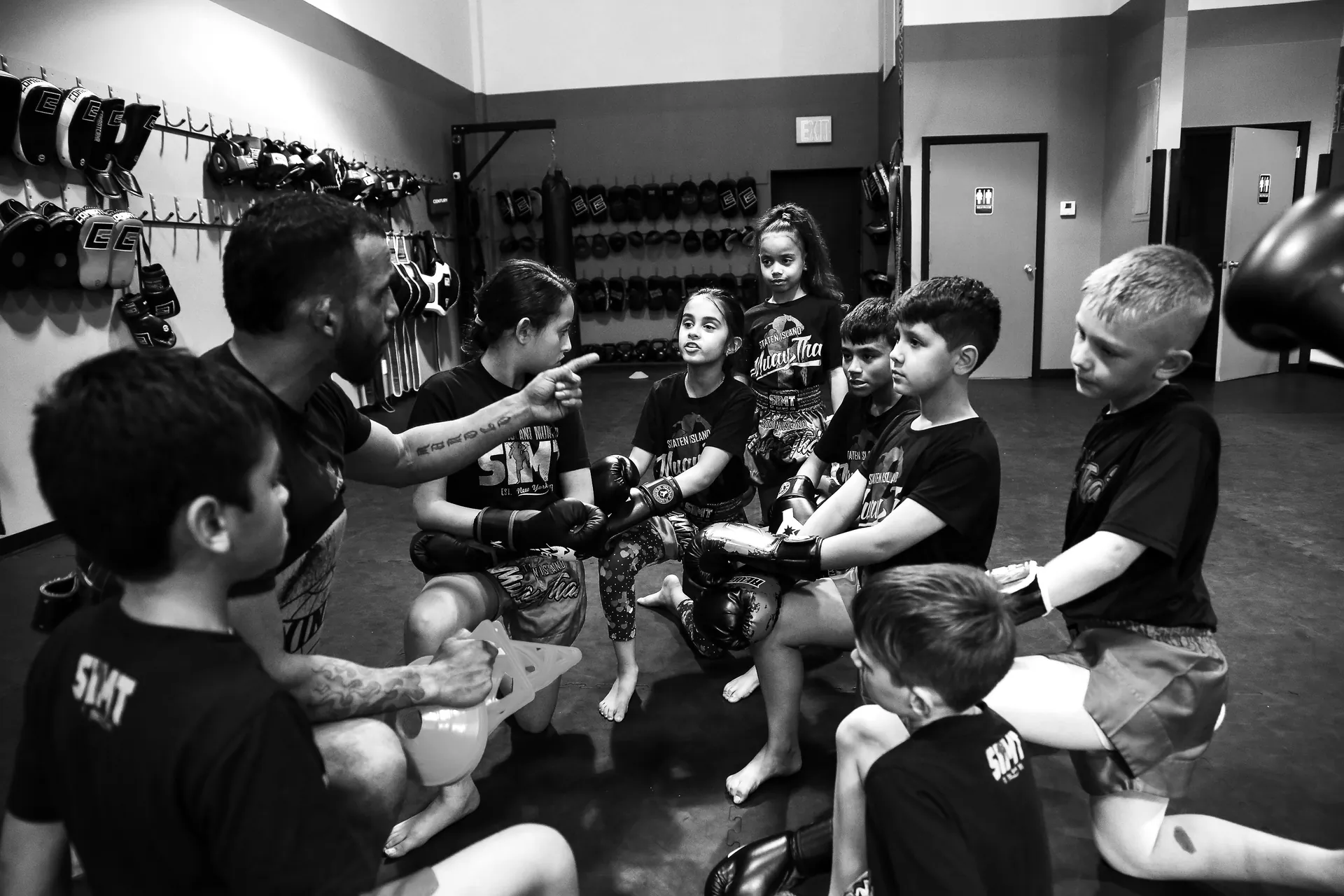 Junior Muay Thai students practicing pad work with instructor